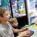 Brothers playing arcade game in amusement park